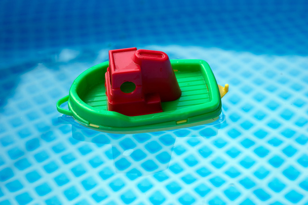 Kleine plastic speelgoed boot in een zwembad - Foto, afbeelding