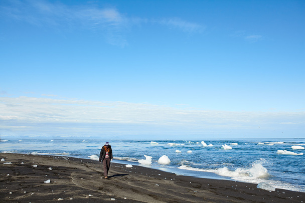 Young woman walking alone on a beautiful beach in Iceland - Фото, изображение