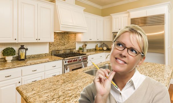 Unelmoiva nainen lyijykynällä kauniissa räätälöidyssä keittiössä
 - Valokuva, kuva