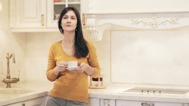 Young beautiful girl enjoying coffee in kitchen - Кадры, видео