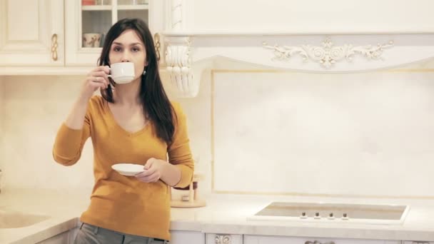 Young beautiful girl enjoying coffee in kitchen - Video, Çekim