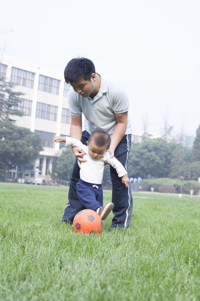 Čínská otec a syn hrát fotbal v louce - Fotografie, Obrázek