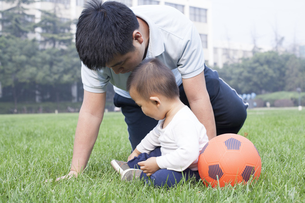 Père et fils chinois jouant au football dans la prairie
 - Photo, image