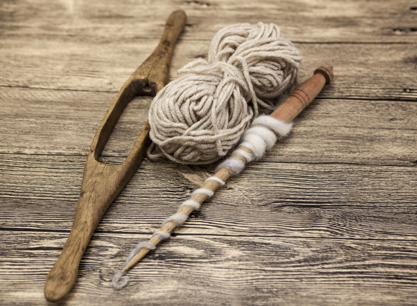 Two old wooden spindle with a ball of wool thread for the manufacture of woolen threads on a wooden background - Foto, immagini