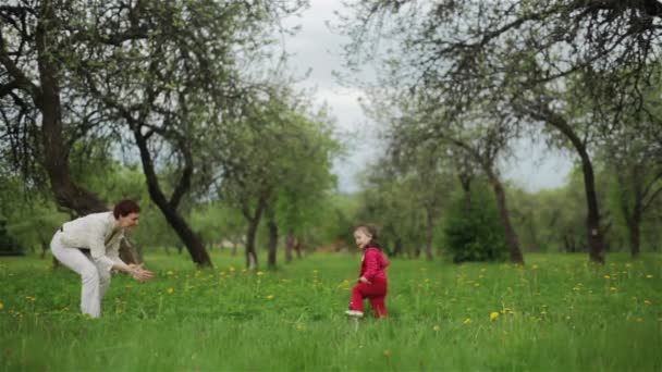 Kislány fut, hogy átfogja az anyja, a nyári kert. Hosszú lövés - Felvétel, videó