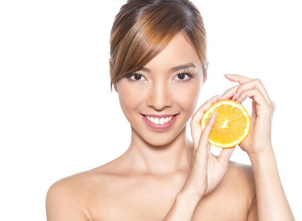 beautiful young asian woman with long hair, flawless skin and perfect make-up, holding orange - 写真・画像