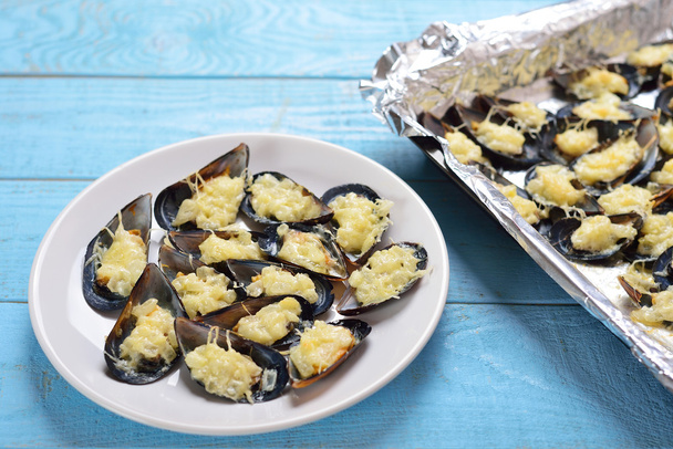 ムール貝の焼きチーズと玉ねぎの青い木製プレート - 写真・画像
