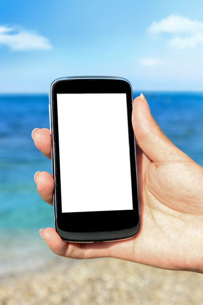 Hand holding mobile phone at the beach - Fotó, kép