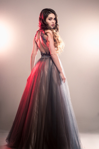 Fashion beauty portrait of gorgeous young woman with long curly hair in luxury evening dress - 写真・画像