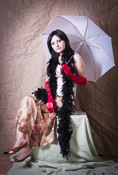 Girl with an umbrella and a boa posing in studio - Fotó, kép