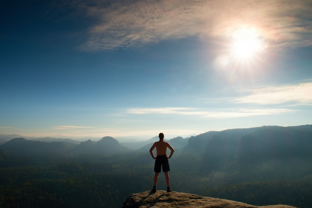 Arrampicante in pantaloni neri. Gesto di trionfo. Corpo nudo uomo sulla cima della roccia arenaria nel parco nazionale Sassonia Svizzera
 - Foto, immagini