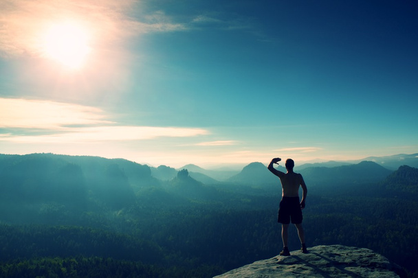 Nahý muž v černé kalhoty pouze na vrcholu hory při západu slunce. - Fotografie, Obrázek