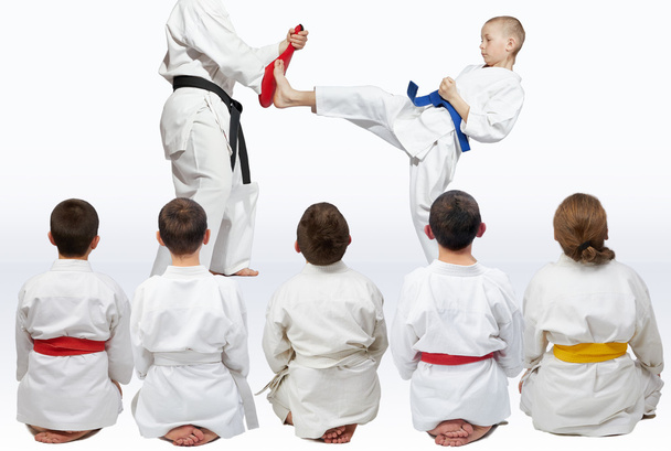 Sporters zitten in pose kijken naar demonstratie punch karate - Foto, afbeelding