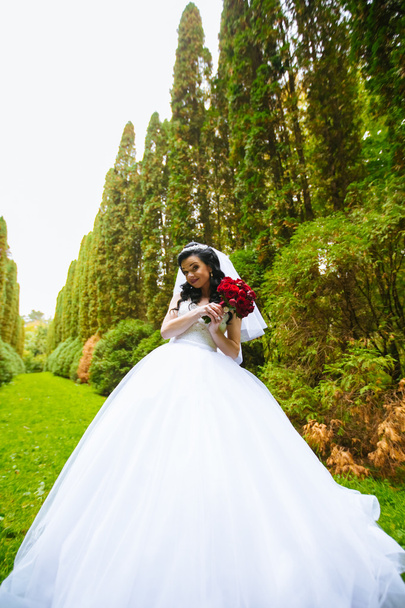Beautiful bride with wedding bouquet of flowers outdoors in green park. - Zdjęcie, obraz