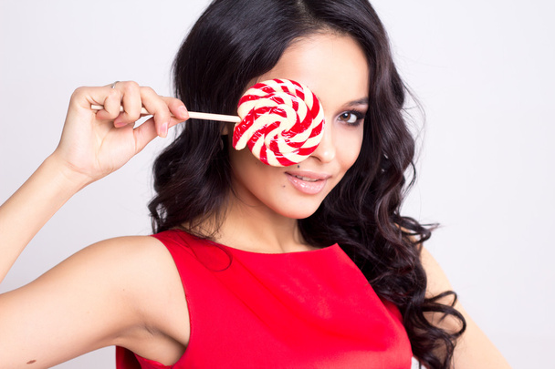 Pretty young woman in red dress with a lollipop - Foto, Imagen