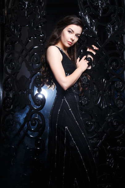 Portrait of elegant young brunette woman in black long evening dress in interior - Foto, Imagem