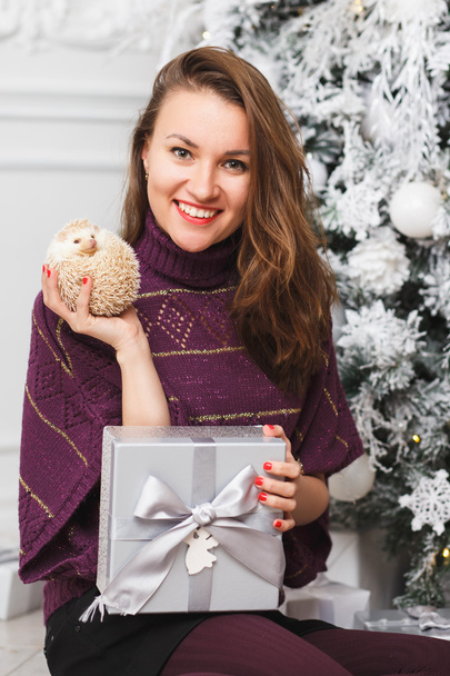 Portrait of a girl in white clothes with a little hedgehog together over light christmas background - Foto, immagini