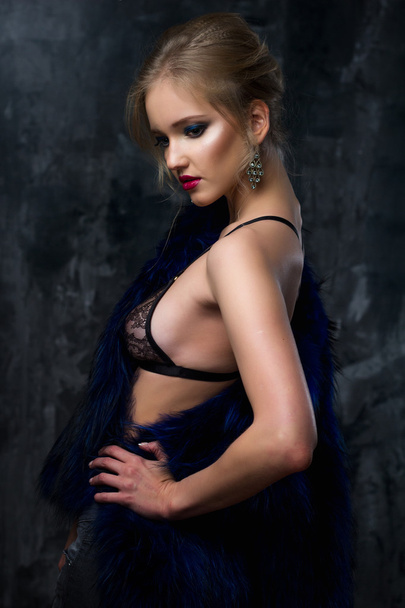 Close-up portrait of gorgeous blonde young woman in celebrity style with perfect make up and hair style wearing sexy lingerie and blue fur. Fashion beauty photo, dramatic look - Photo, Image
