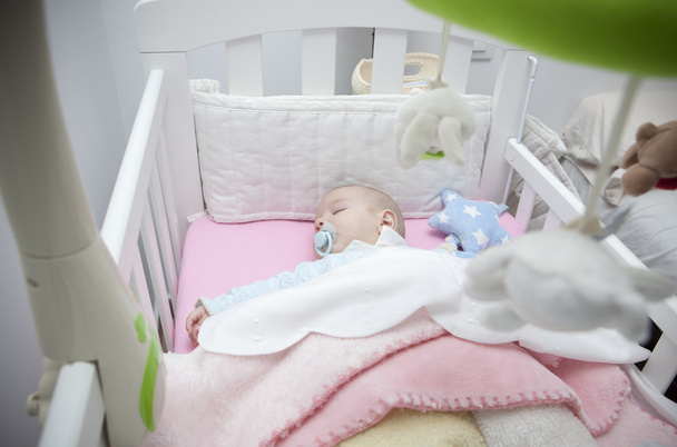 Nukkuu neljän kuukauden poikavauva makaa sängyssä mobiili
 - Valokuva, kuva