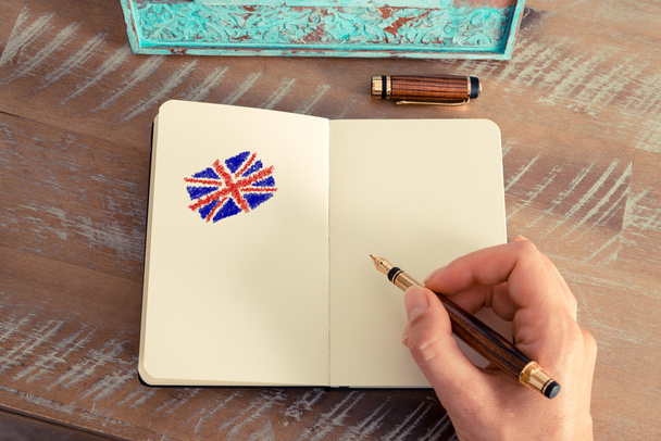 Woman hand drawing the Union Jack flag on notebook - Photo, Image