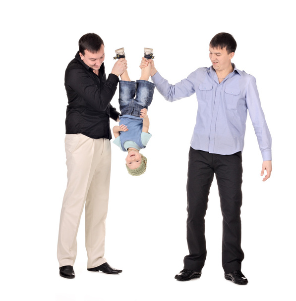 dva gusd drží malého chlapce vzhůru nohama - Fotografie, Obrázek