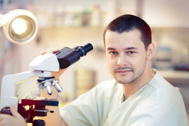 Молодий чоловік вчений з мікроскопом - Фото, зображення