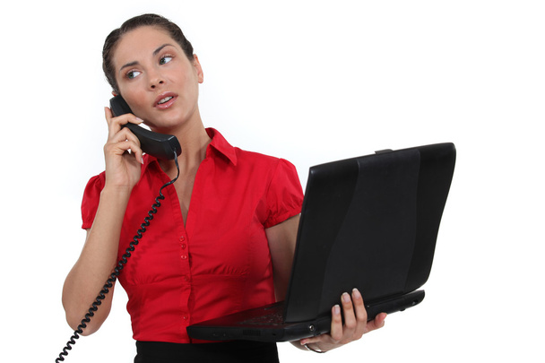 Secretary holding a laptop while talking on the phone - Фото, зображення