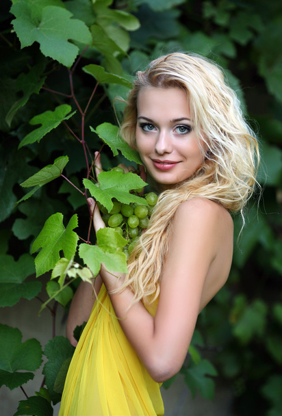 Portrait of a beautiful young blonde with a bunch of grapes - Foto, immagini