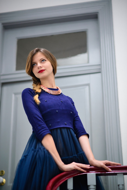 elegant woman in blue dress poses on the stairs - Foto, afbeelding