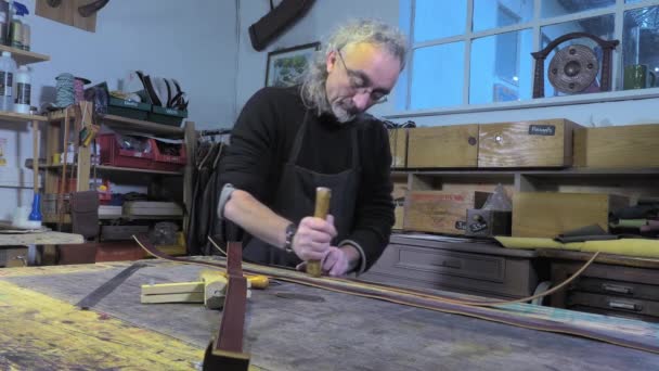 Δερμάτινα εμπορεύματα τεχνίτης στην εργασία στο εργαστήριό του - Πλάνα, βίντεο
