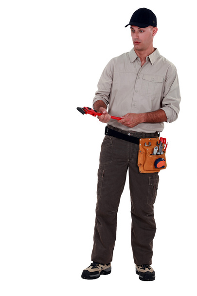 Amazed man holding a pipe wrench - Foto, afbeelding