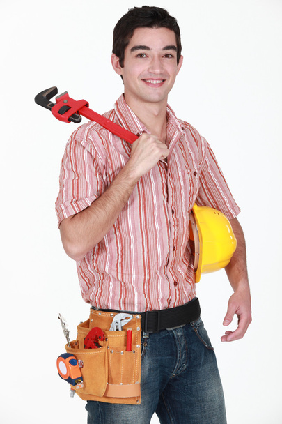 Young man with a hardhat and a wrench - 写真・画像