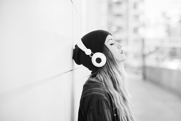 woman leaning against wall listening music - Photo, Image