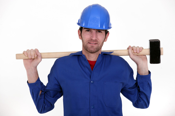 Craftsman in blue overalls holding huge hammer - Фото, зображення