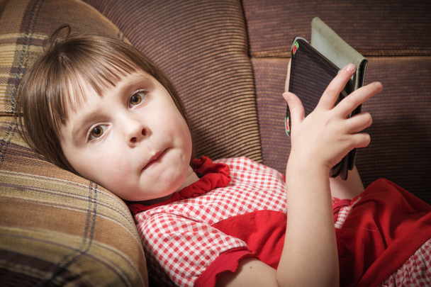 Little girl playing with a modern digital tablet. - 写真・画像