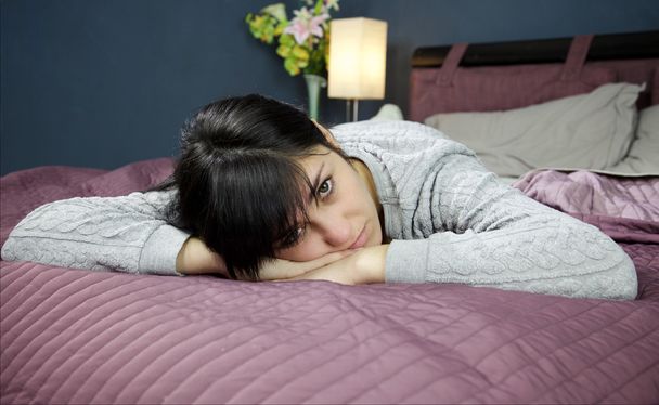 Smutna dziewczyna w łóżku patrząc aparatu niezadowolony leżącego - Zdjęcie, obraz
