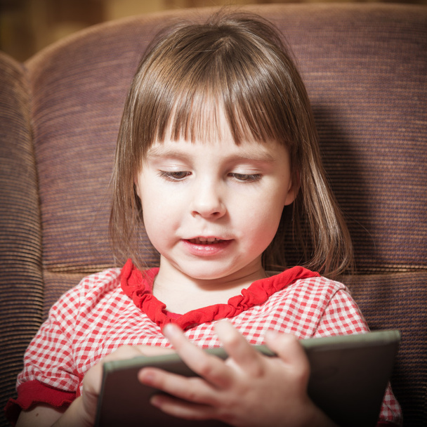 Little girl playing with a modern digital tablet. - 写真・画像