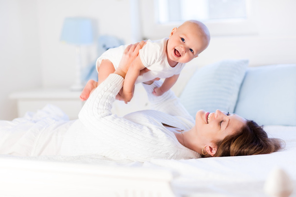 Mother and baby on a white bed - Foto, afbeelding