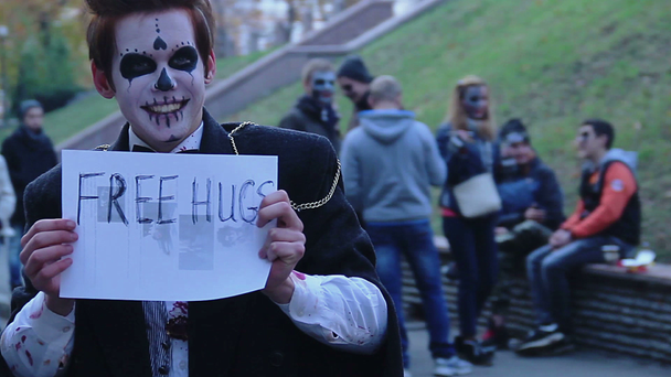 Onnellinen teini yllään pelottava zombie puku hymyilee ihmisille, tarjoaa ilmaisia halauksia
 - Materiaali, video