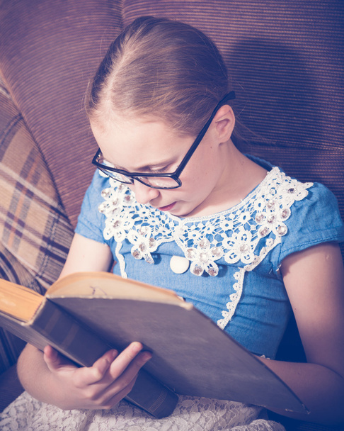 Girl reading a book at home sitting in an armchair. - Φωτογραφία, εικόνα