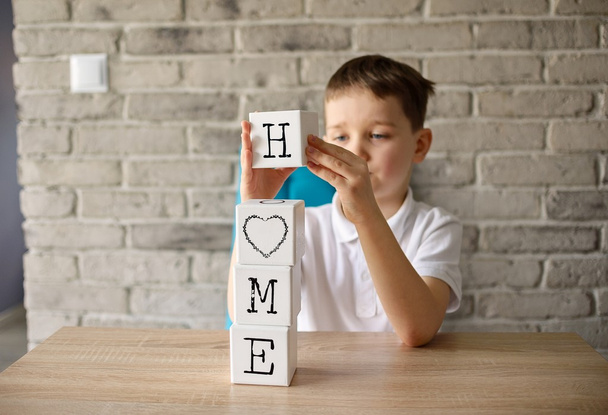 6 ετών αγόρι κρίνοντας παίζει άλλα-Δοκοροί με γράμματα κάνοντας λέξη σπίτι - Φωτογραφία, εικόνα