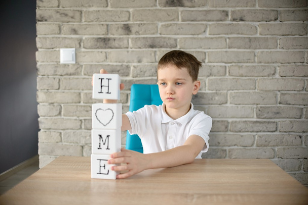 Маленький хлопчик грає з кубиками і кладе його в слово "домашній"
"  - Фото, зображення