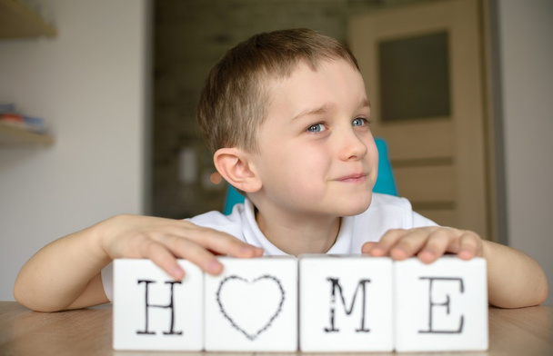 Šťastný chlapec hraje s kostkami a dává dohromady v slovo "domov".  - Fotografie, Obrázek