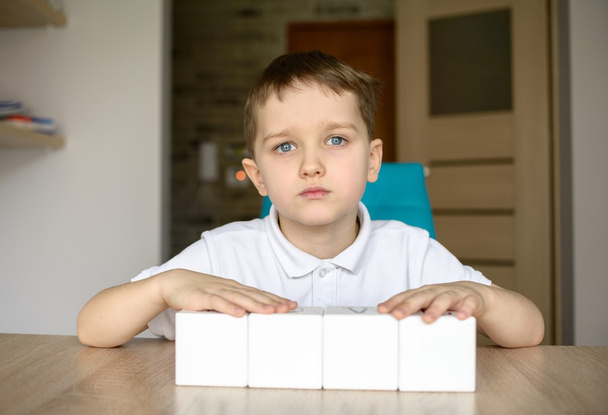 Boy plays with white cubes. Place for your text . - Photo, Image