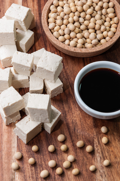 Соевый соус, кусочек тофу и соевых бобов на деревянной доске
 - Фото, изображение