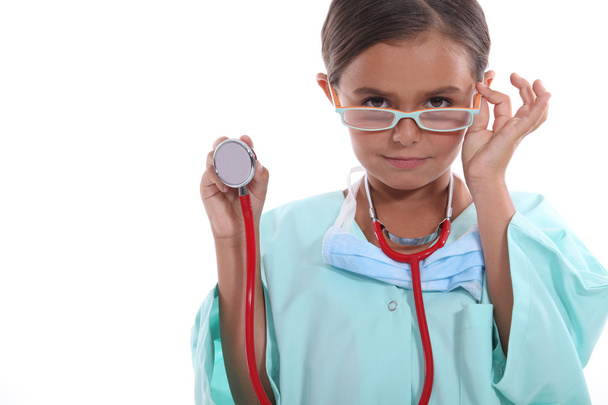 Child wearing grown up hospital scrubs, glasses and a stethoscope - Фото, изображение