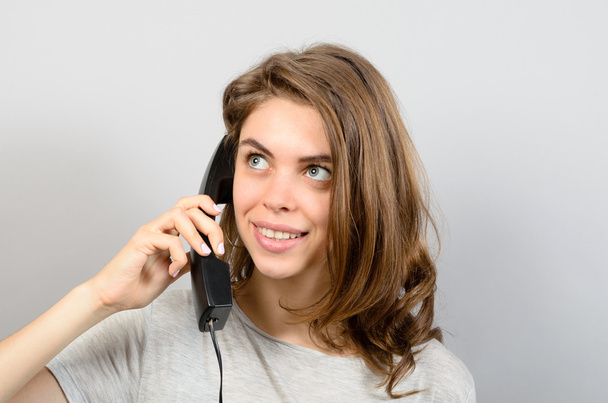 Happy young woman using phone against grey background - Foto, Imagem