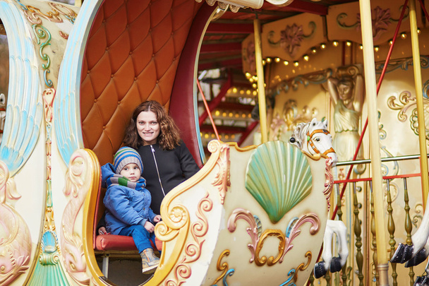 Young mother with her adorable little son on Parisian merry-go-round - Photo, image