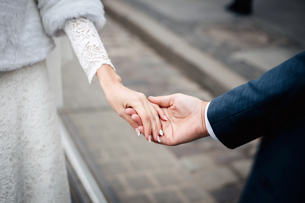 Braut und Bräutigam halten Händchen im Freien - Foto, Bild