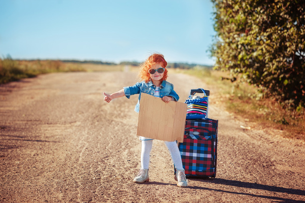 Little curly girl with suitcase  hitchhiking and standing about  - Fotoğraf, Görsel